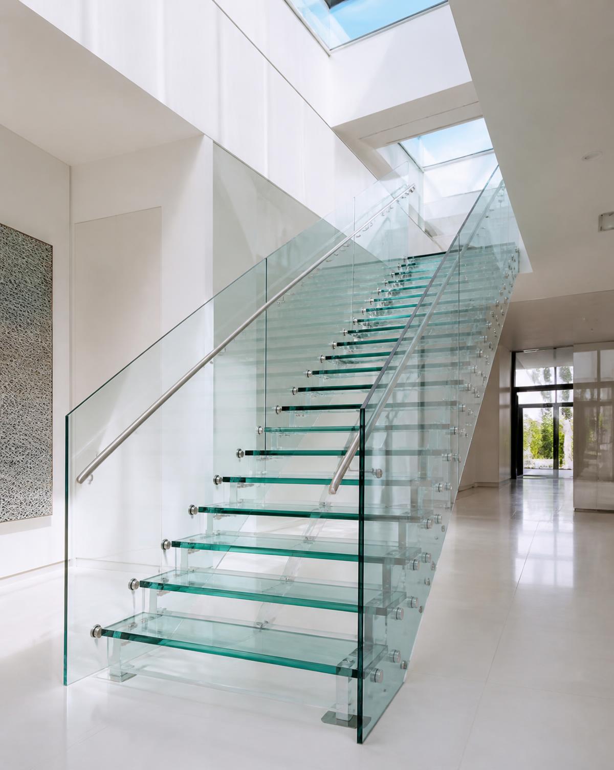 Scala con gradini in vetro stratificato e parapetto in vetro in un atrio bianco